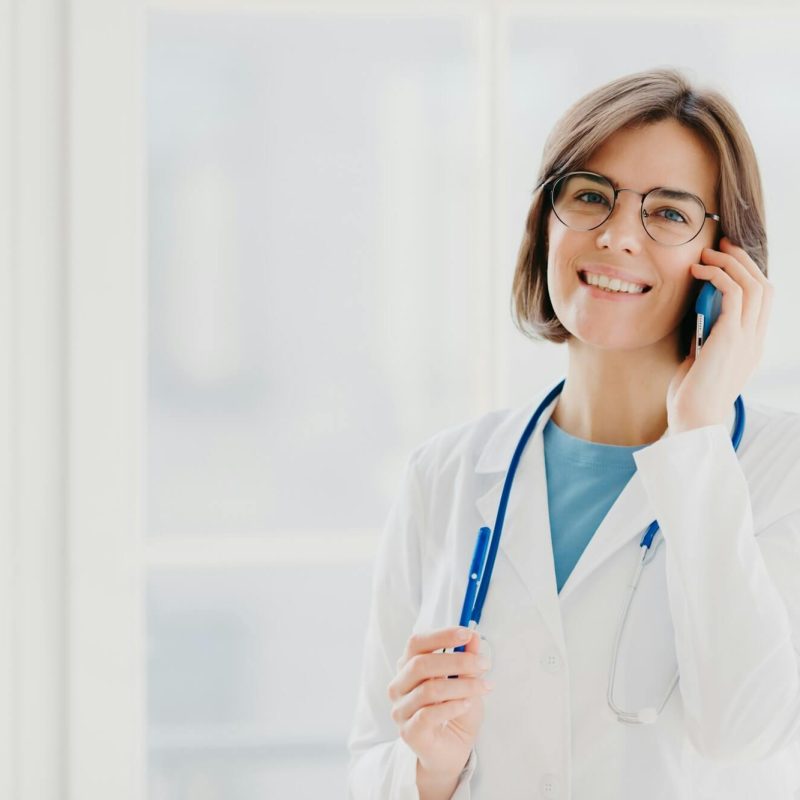 positive-woman-doctor-consults-patient-via-cellphone-looks-gladfully.jpg